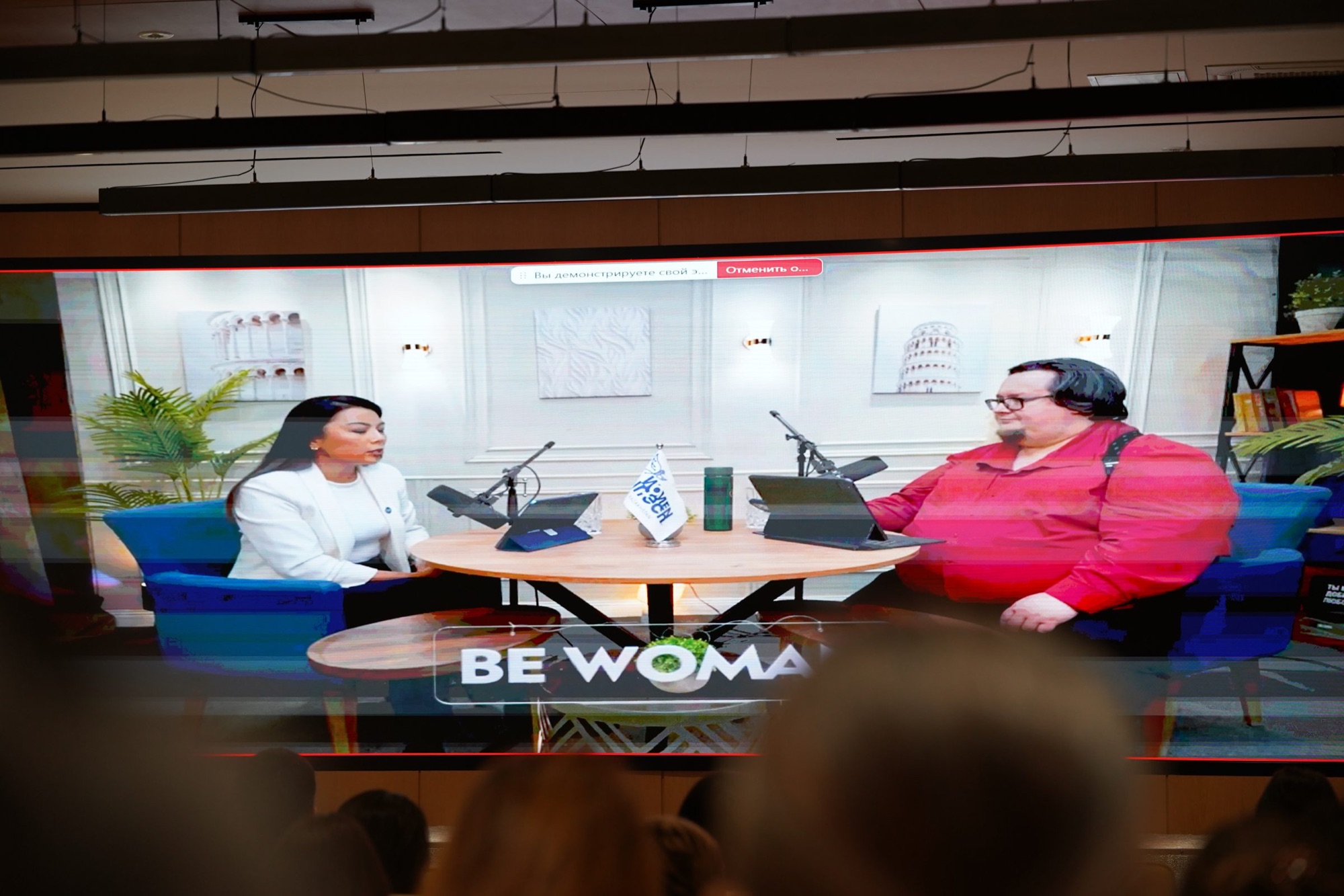 Clips from the Aman Bol podcast on screen during the event